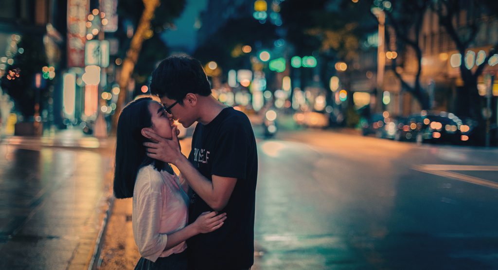 Lovers kiss in the street in rainy night